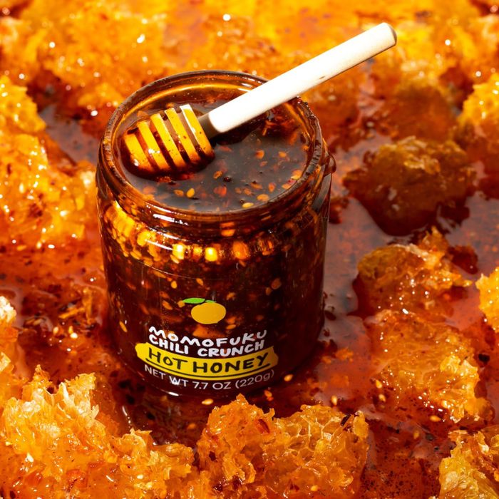A jar of Momofuku Chili Crunch Hot Honey surrounded by honeycomb pieces, adding an extra layer of flavor and texture.