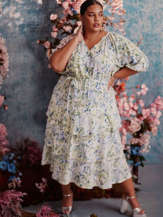 Model wearing a white tiered dress adorned with a beautiful blue and green pattern.