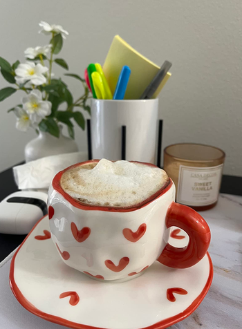 A white mug and plate featuring squiggly red-lined edges, decorated with small red hearts, creating a fun and whimsical design.