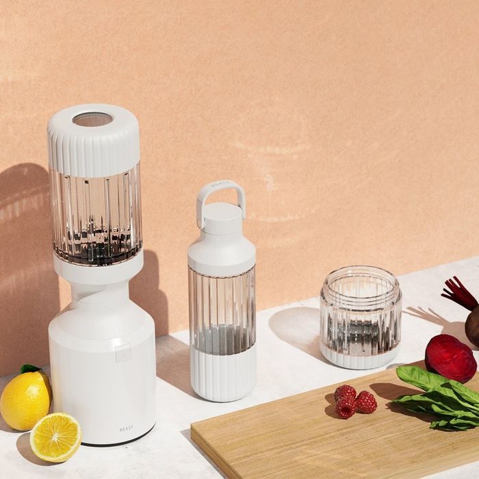 A sleek blender set with a contemporary design, placed on a kitchen counter surrounded by fresh fruits and vegetables.