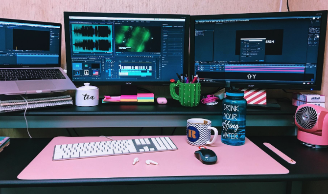 A pink version placed on a desk, accompanied by a keyboard, wireless mouse, and a mug.