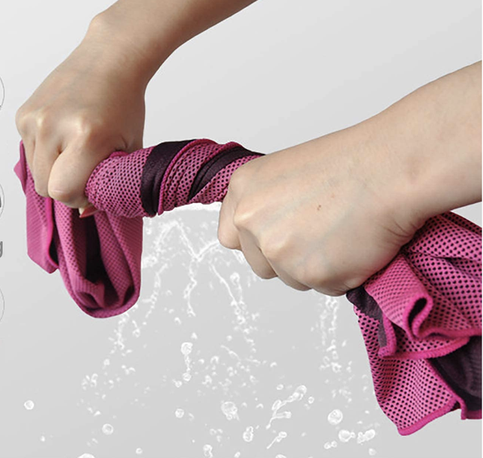 A person squeezing a microfiber towel with water dripping from it.