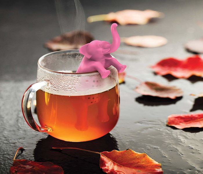 An elephant-shaped tea diffuser nestled inside a tea cup.
