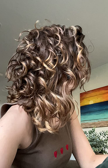 An image of the reviewer displaying shiny, curly hair after using the diffuser.