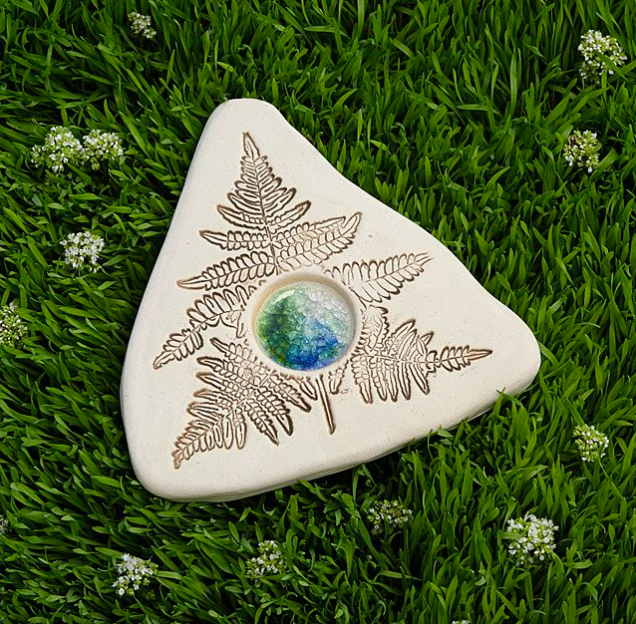 A triangular stone engraved with a leaf pattern, featuring a central water-collecting section.