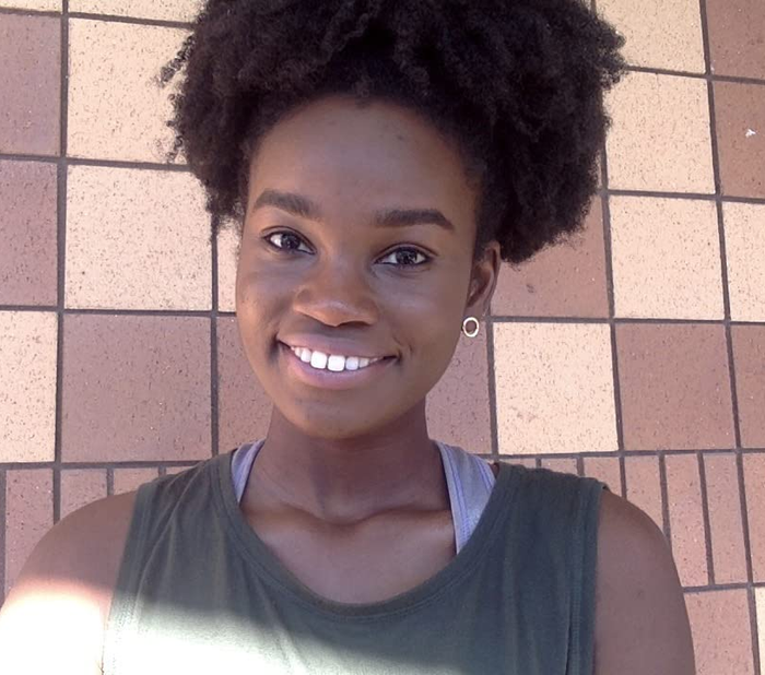 A picture of a Black reviewer with coily hair tied up in a ponytail