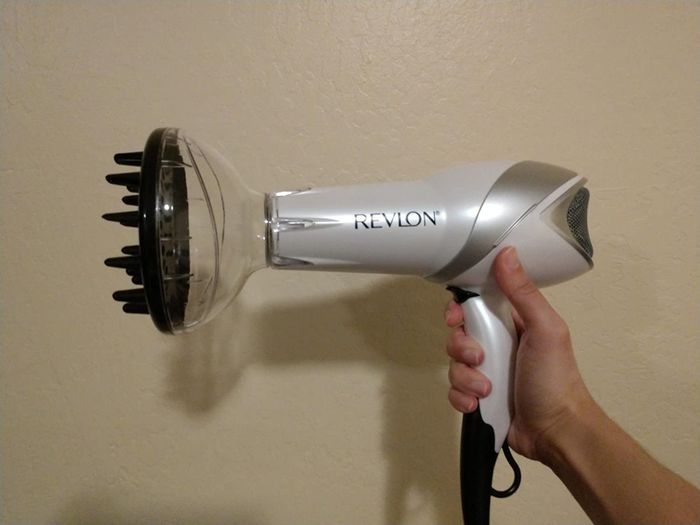 A reviewer's image showing the Revlon hair dryer with the diffuser attachment in use.