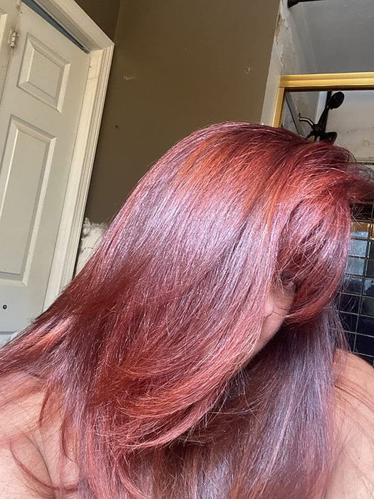 An image of a reviewer sporting shiny, healthy, and straight red hair.