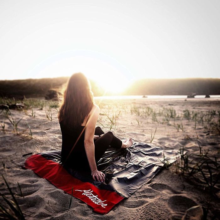 A person relaxing on the blanket at the beach, watching a serene sunset unfold before them.