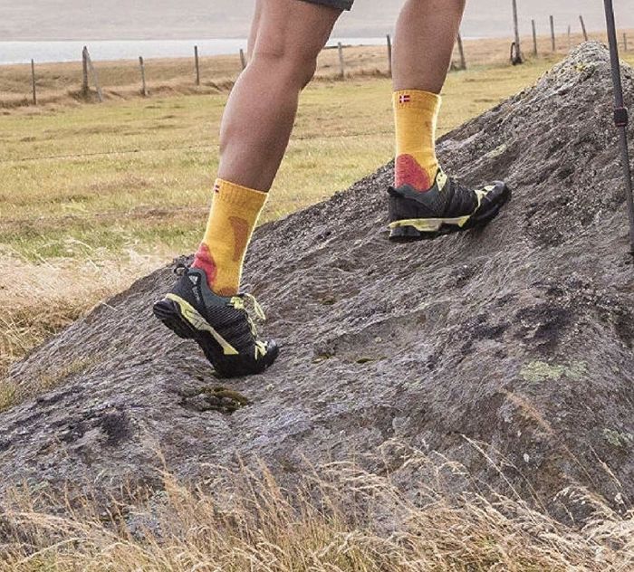 A person is wearing socks while climbing up a rocky surface.