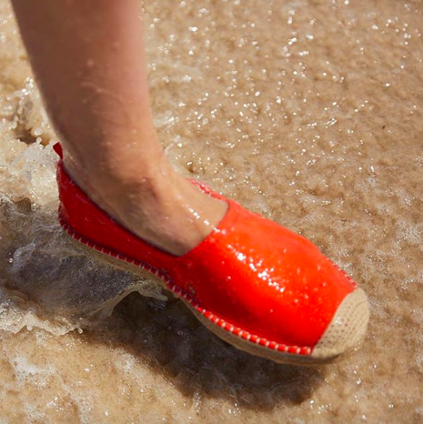 A foot wearing the espadrille shoes in the ocean water