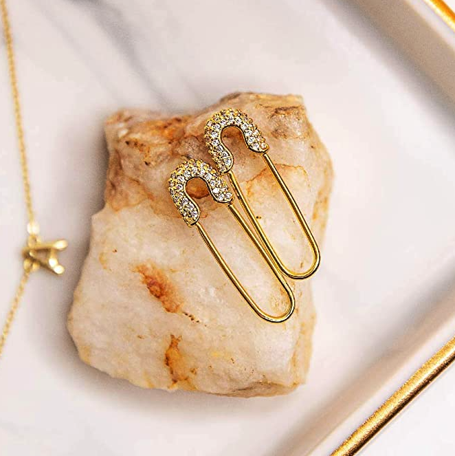 A close-up of safety-pin style earrings displayed on a crystal.