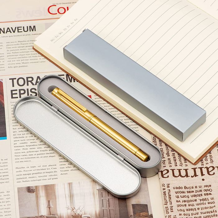 The gold fountain pen, neatly stored in its case, placed beside a notepad.