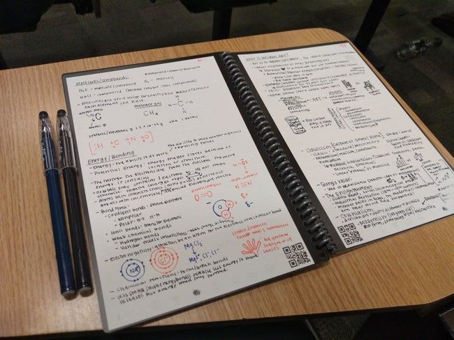 A reviewer’s image of the notebook open on a desk, with neatly written notes on both sides and two pens resting beside it.