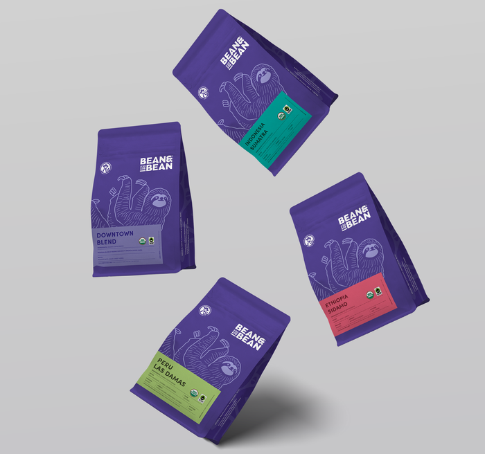 Four purple bags of various coffee bean varieties.