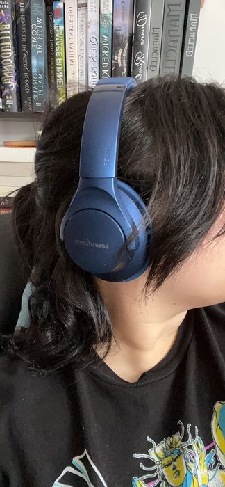 A reviewer wearing the blue pair of headphones