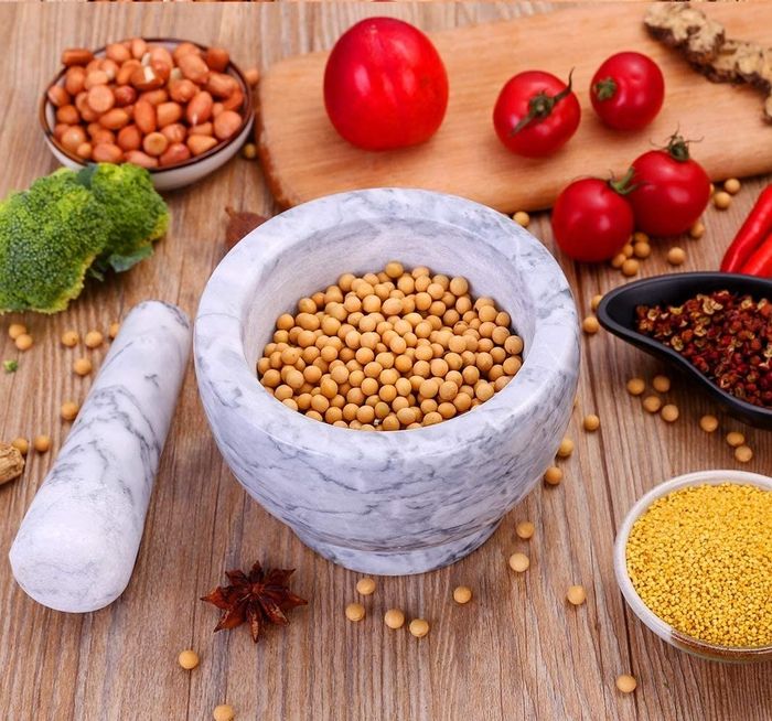 The gray mortar filled with spices and surrounded by various cooking ingredients.