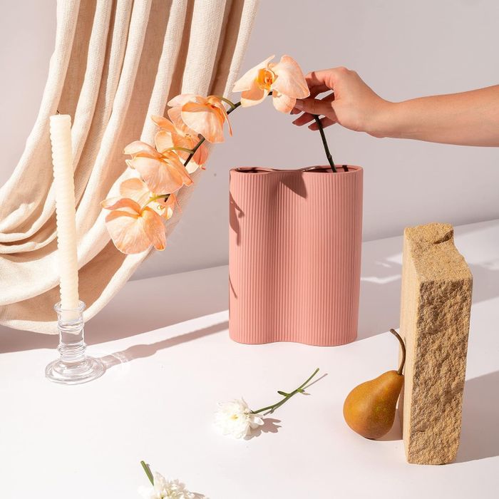 A model gracefully placing a flower into a pink vase.