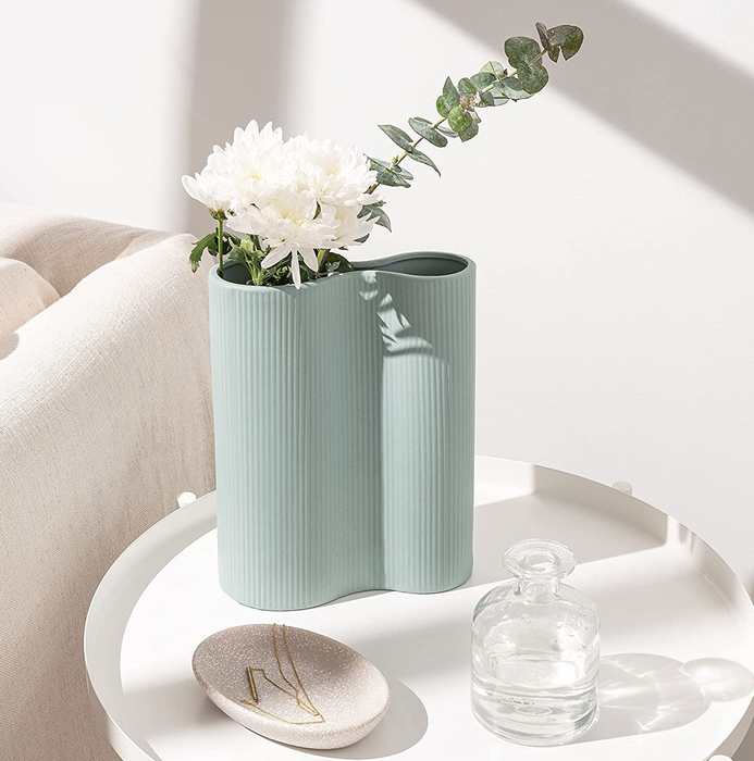 A blue vase, holding white flowers, placed on a small table adorned with charming trinkets.