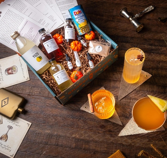 A festive cocktail kit complete with mixers and mini pumpkins, encircled by drink glasses and cocktail essentials.