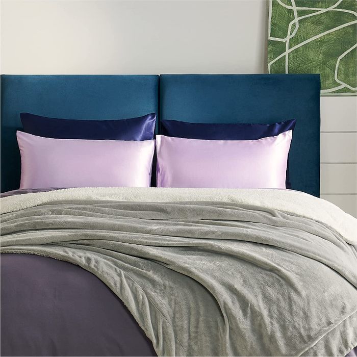 The lavender and navy satin pillowcases elegantly displayed on pillows