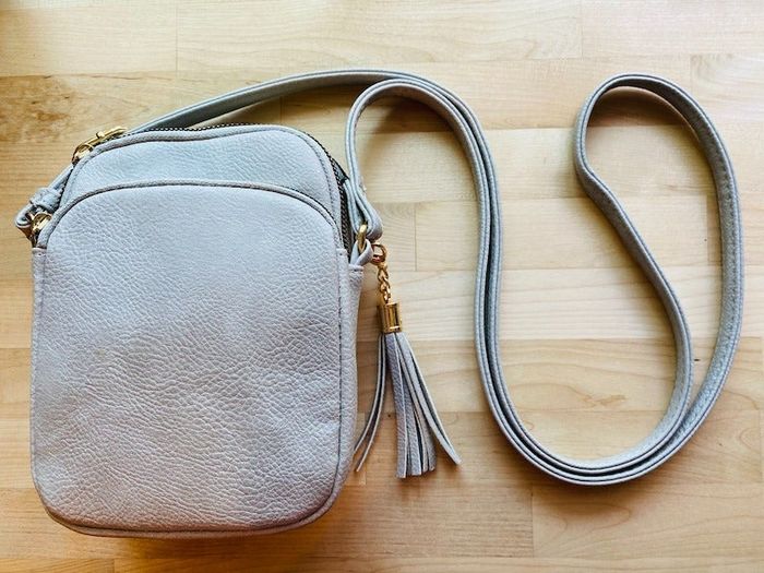 A reviewer showcasing a light gray purse