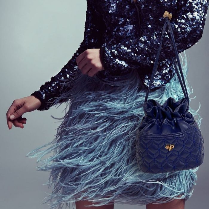 Someone wearing the blue purse, paired with a party skirt and a sequin blazer.