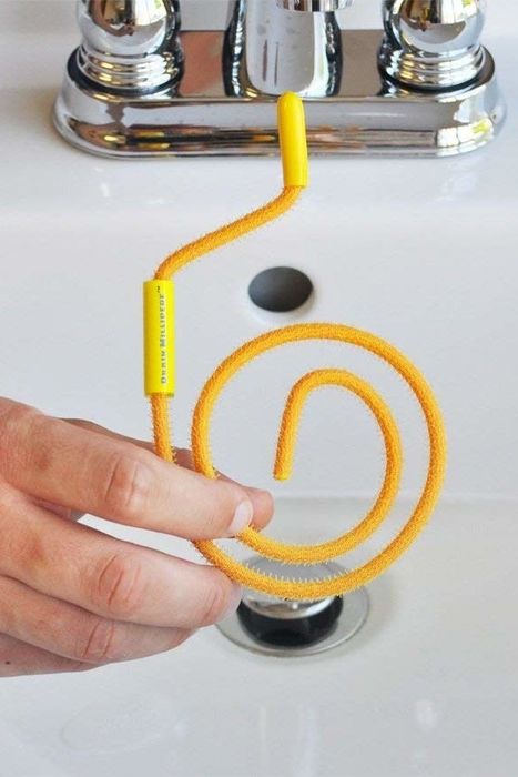a person holding a coiled hair remover in front of a sink
