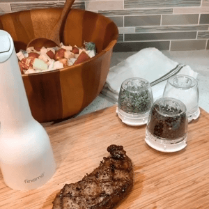 a gif of someone placing a spice pod into the grinder and grinding fresh spice over a steak