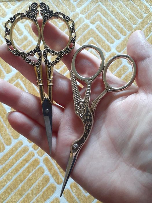 A reviewer holding both sets of elegant gold scissors in their hands