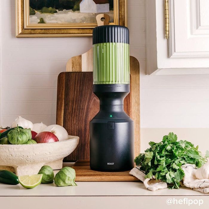 A black blender, perfectly blending a fresh green smoothie.