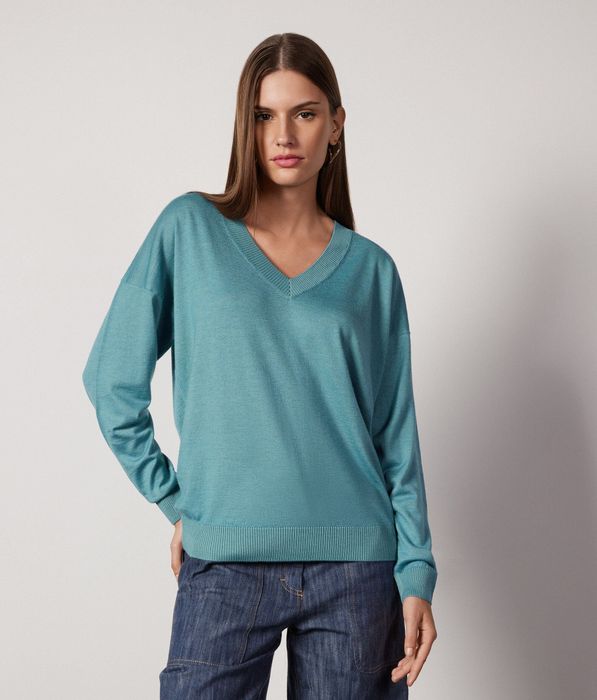 A model showcasing the V-neck cashmere sweater in a serene ocean color.