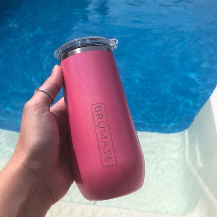 A reviewer pictured holding the insulated champagne flute in a radiant hot pink shade.