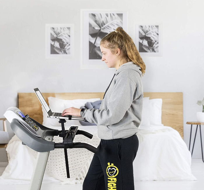 A person walking on a treadmill, with their laptop propped up in front for a mobile workstation.