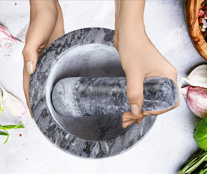 A top-down view of hands holding the black mortar and pestle.
