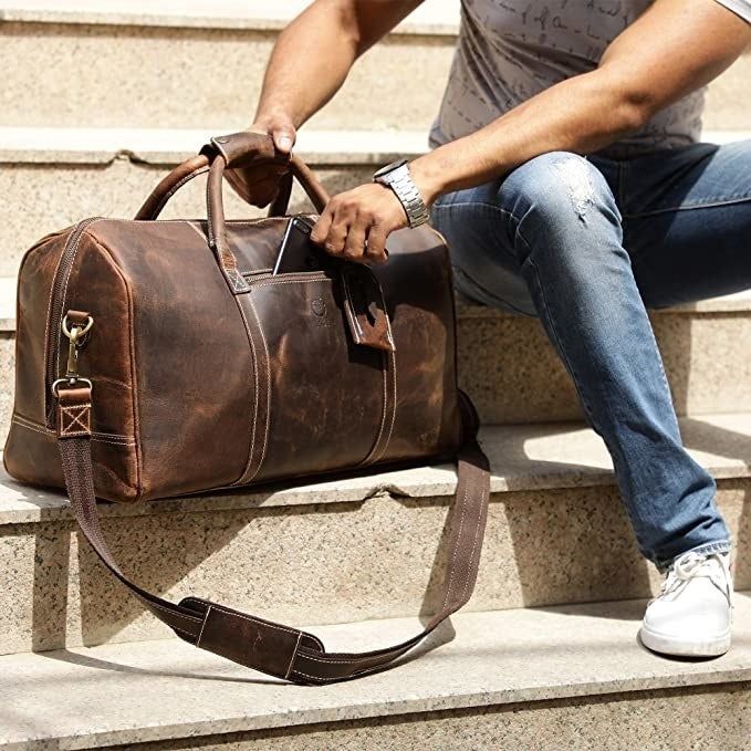 A different model sitting on the stairs beside the bag, placing their phone into the outer pocket.
