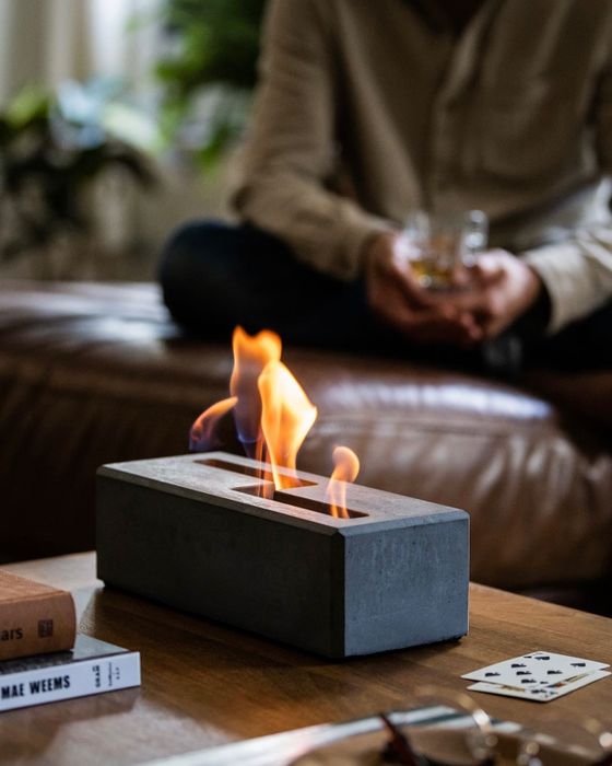 A photo showcasing the concrete fireplace glowing warmly.