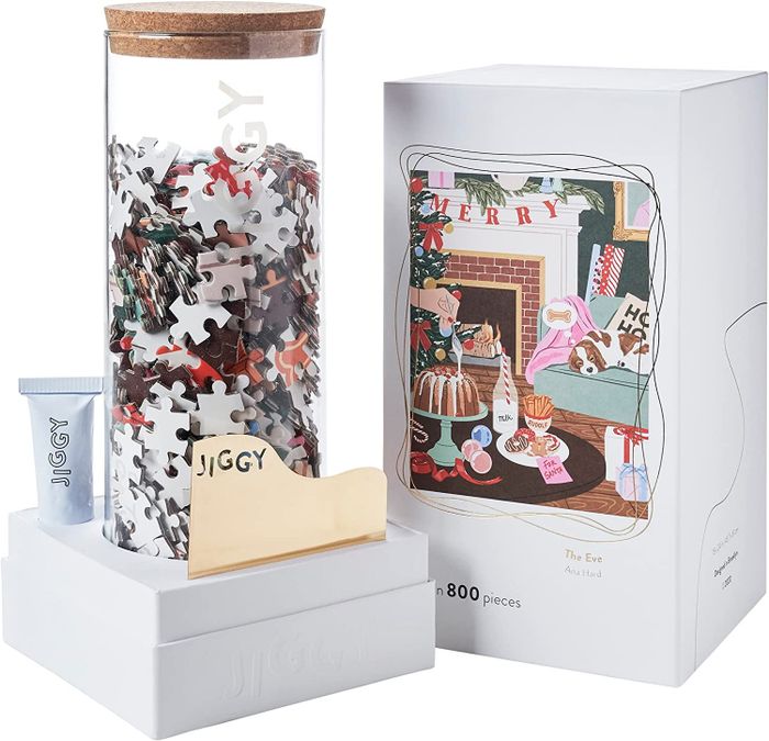 The puzzle box placed beside a glass jar filled with the puzzle pieces and a tube of glue.