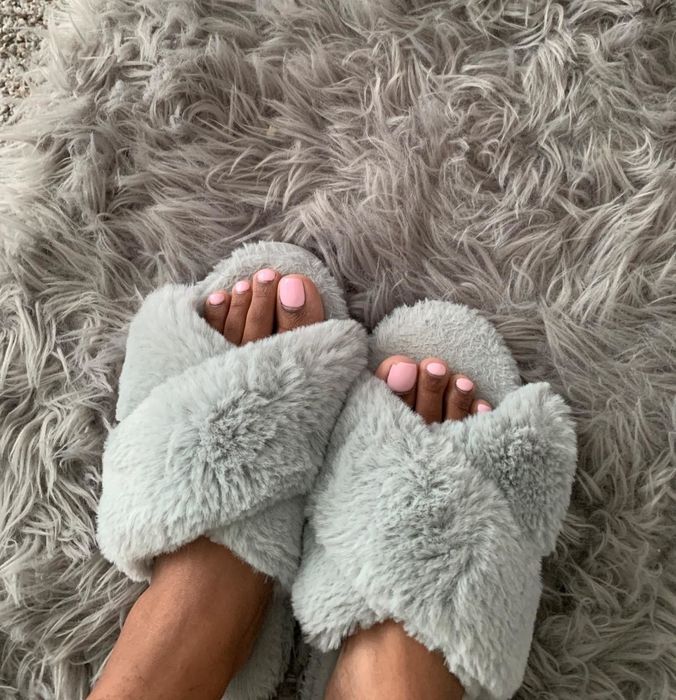 A reviewer showing off the grey slippers