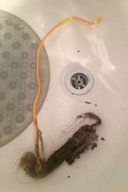 a reviewer's photo showing the hair remover covered in a large ball of collected hair
