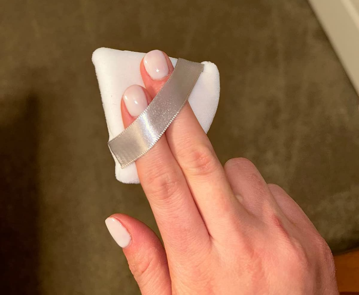 A reviewer holds the powder puff, highlighting its ease of use and effectiveness.