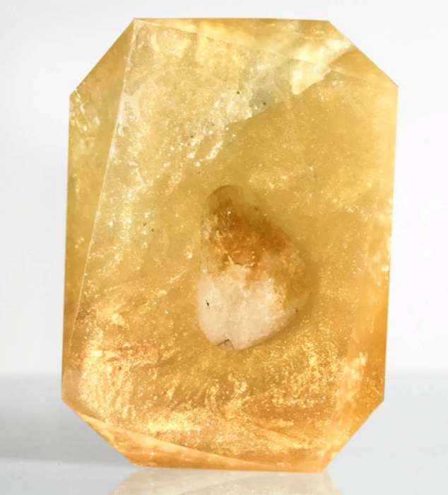 A golden soap bar featuring a crystal in the middle.