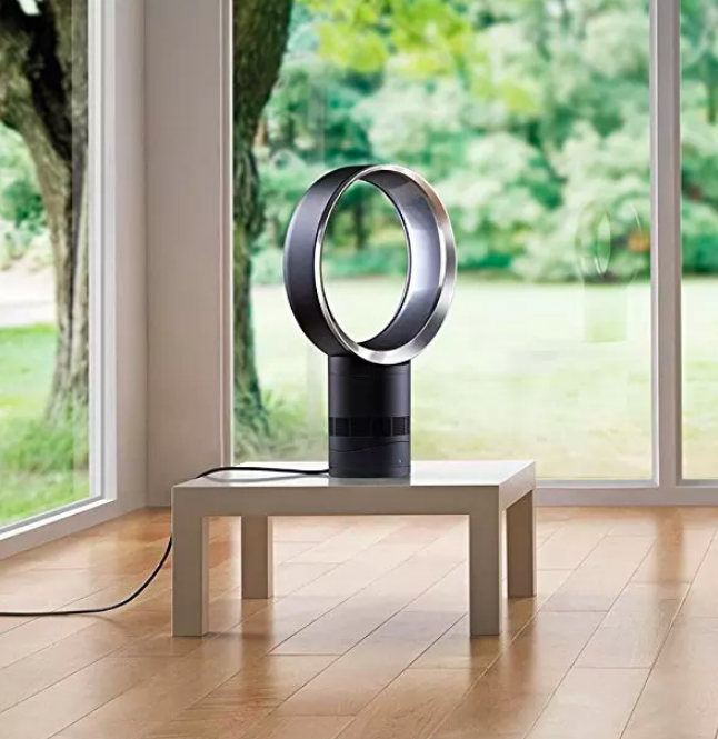 A picture of the fan positioned in the corner of a room, occupying the center of a small side table.