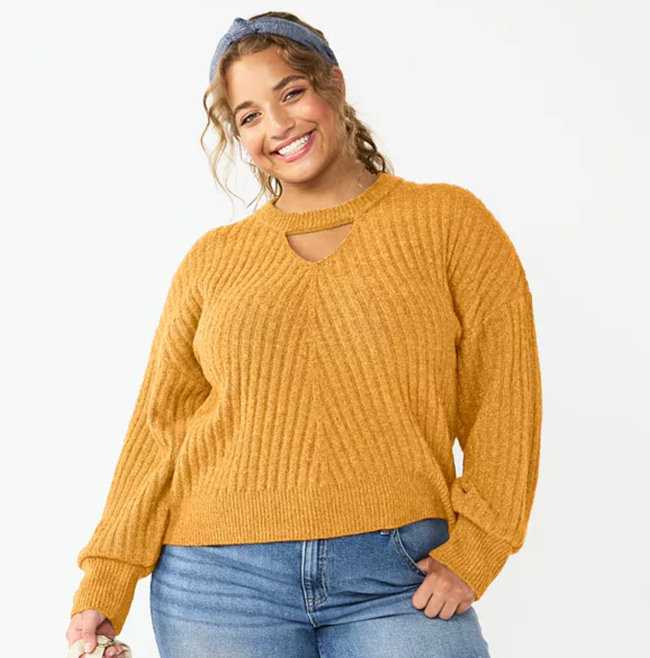 A model is seen wearing the keyhole sweater in a rich mustard shade, paired with jeans for a chic look.