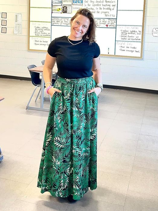 The reviewer is wearing a green floral skirt.