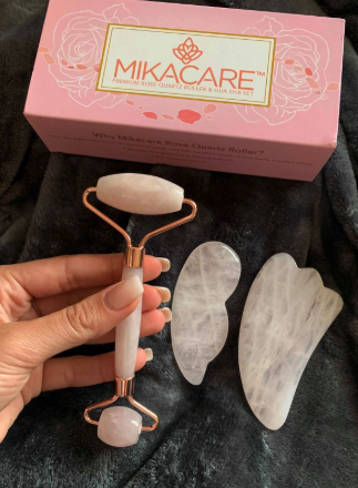 A reviewer holding the pink rose quartz roller next to the gua sha