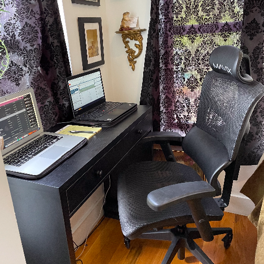 The chair positioned in a small bedroom corner, between the bed and a slim desk.