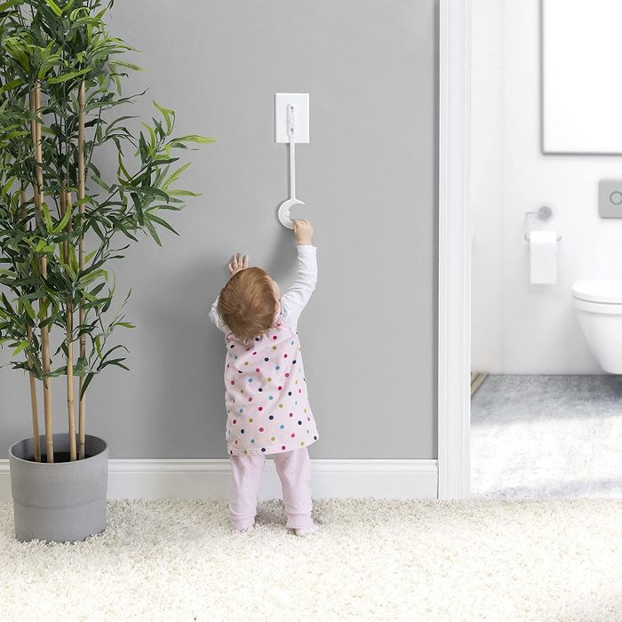 A child reaching up to grab the light switch extender