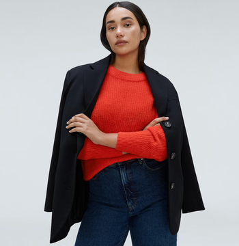 Model styled in a red sweater under a black blazer with jeans