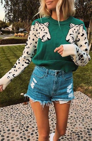 A model wears a stylish leopard print sweater paired with cut-off shorts for a chic, laid-back look.